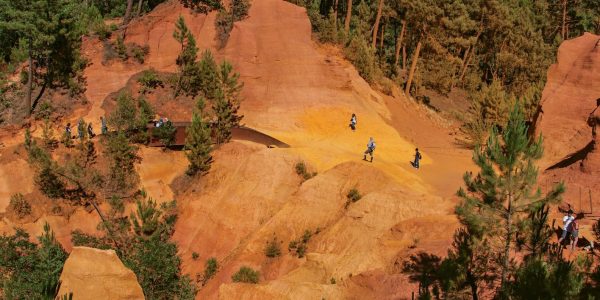 Roussillon, France - July 03, 2016. View of ocher land and people in the park "Sentiers des Ocres" under a sunny blue sky, near the village of Roussillon. Located in the Vaucluse department, Provence region, in southeastern France