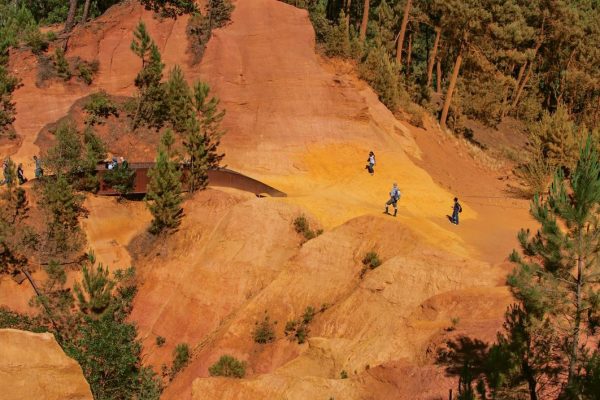 Roussillon, France - July 03, 2016. View of ocher land and people in the park "Sentiers des Ocres" under a sunny blue sky, near the village of Roussillon. Located in the Vaucluse department, Provence region, in southeastern France