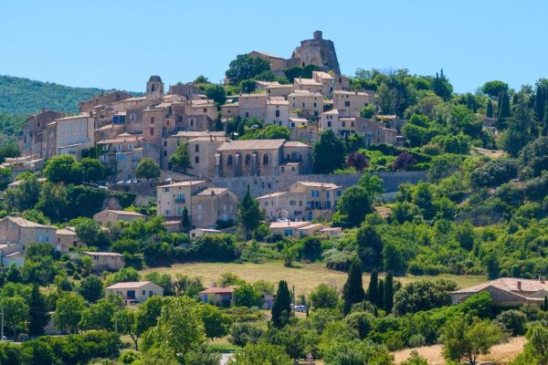 City of Saint-Saturnin-les-Apt on the hill with lavender fields in valley on summer day. Provence, France